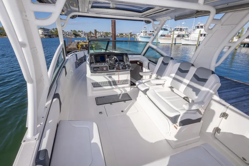 Slide: The Image of 2020 Chaparral 300 OSX boat interior with helm and seating, docked by the water. - 31