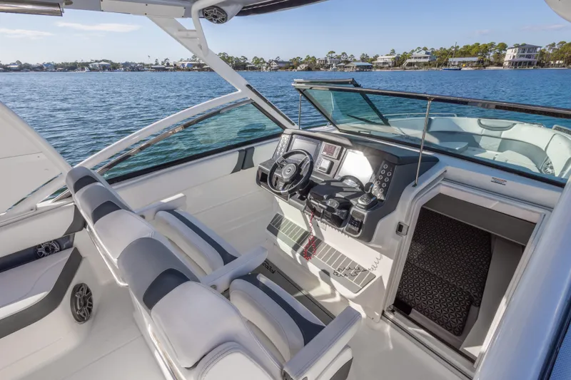 Slide: The Image of 2020 Chaparral 300 OSX boat cockpit with dual seats and modern controls on a sunny day. - 37