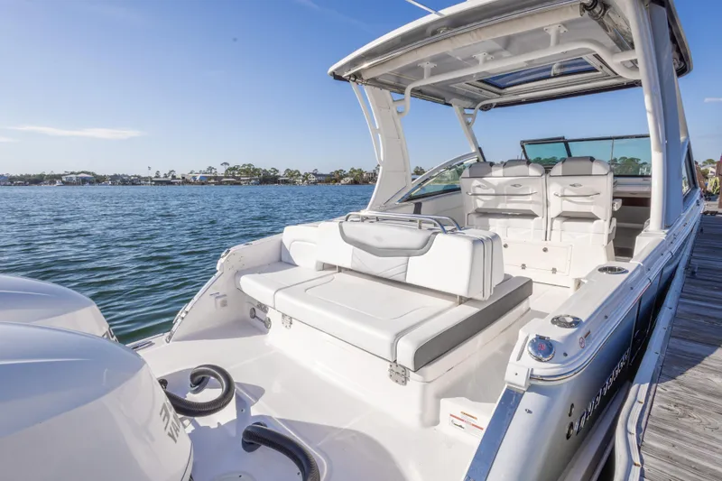 Slide: The Image of 2020 Chaparral 300 OSX boat docked by the water, showcasing spacious seating and sleek design. - 43