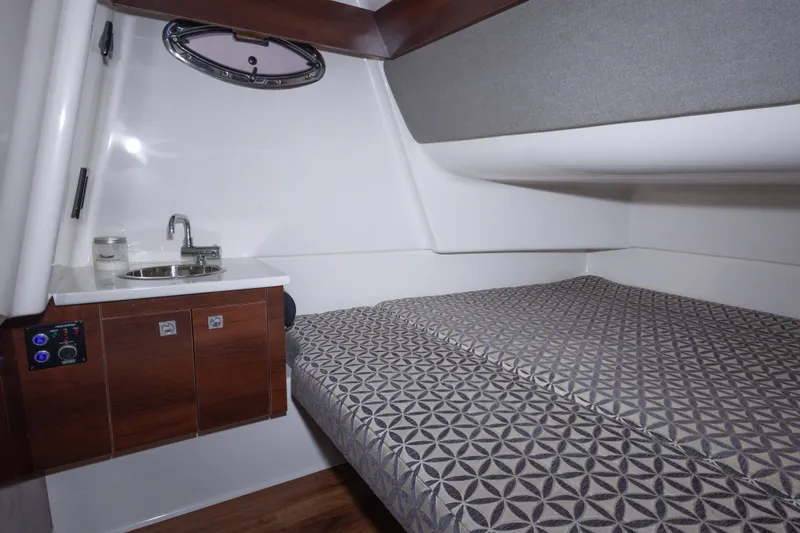 Slide: The Image of 2020 Chaparral 300 OSX cabin interior with bed and sink area. - 49