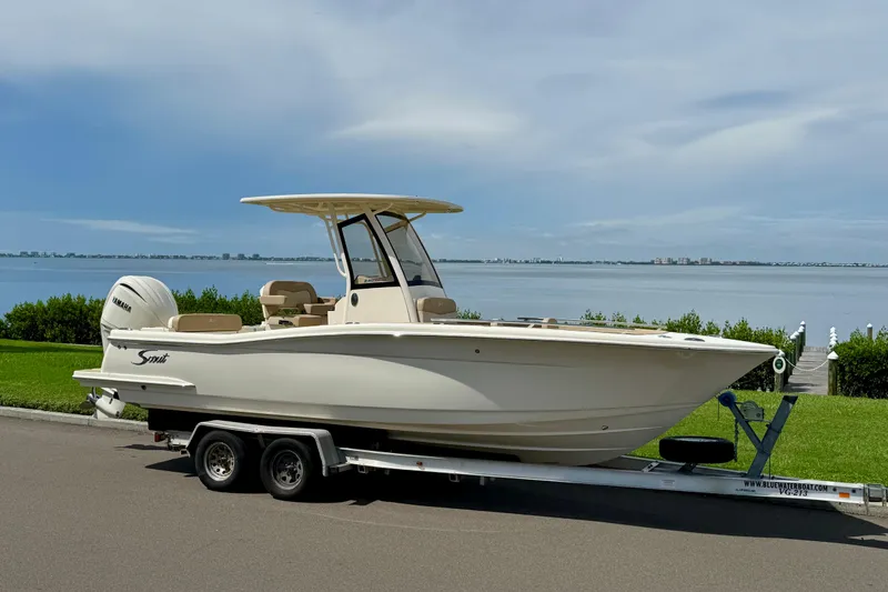The Image of 2025 Scout 240 XSF boat on trailer by waterfront, clear sky background. - 0