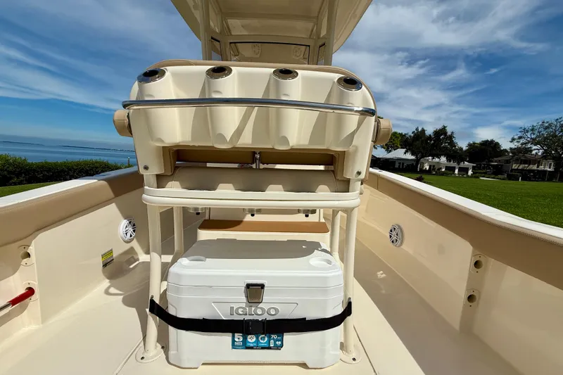 Slide: The Image of 2025 Scout 240 XSF boat interior with cooler and rod holders, scenic waterfront view. - 11