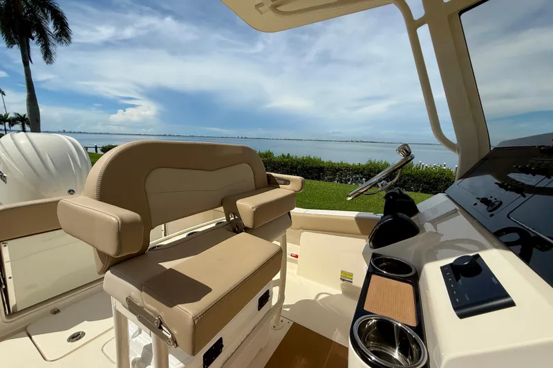 Slide: The Image of 2025 Scout 240 XSF boat interior with steering wheel, overlooking serene waterfront. - 14