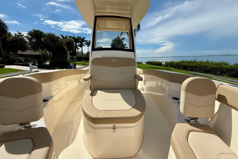 Slide: The Image of 2025 Scout 240 XSF boat interior with beige seating, set against a scenic waterfront view. - 17