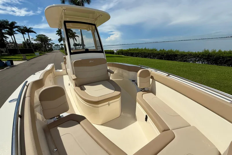 Slide: The Image of 2025 Scout 240 XSF boat with beige seating, parked near waterfront, under clear sky. - 18