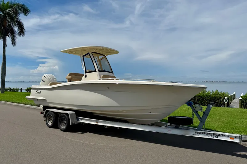 Slide: The Image of 2025 Scout 240 XSF boat on trailer by waterfront, under clear sky. - 3