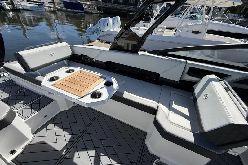 Slide: The Image of 2024 Cobalt R8 Outboard boat interior with seating and table, docked by the water. - 6
