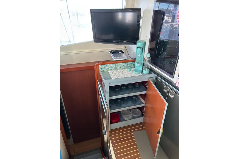 Slide: The Image of Compact kitchen area in a 2013 Leopard 48 yacht with open cabinet and TV. - 48