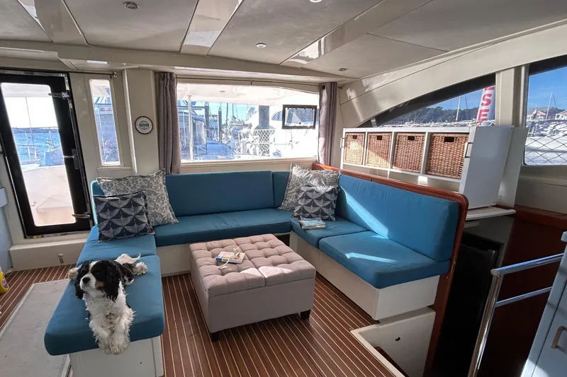 Slide: The Image of Luxurious 2013 Leopard 48 yacht interior with blue seating, dog, and scenic marina view. - 49