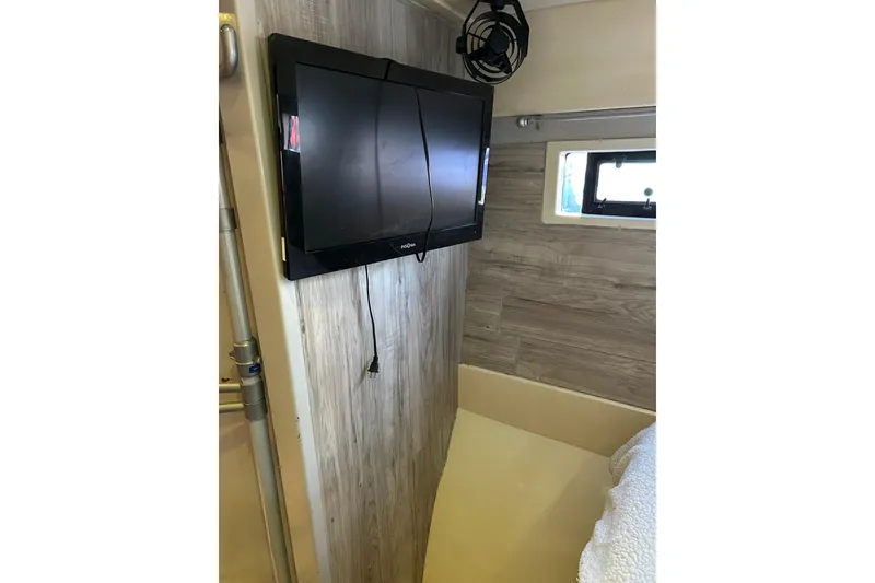 Slide: The Image of Wall-mounted TV in 2013 Leopard 48 yacht cabin with wood paneling and small window. - 60