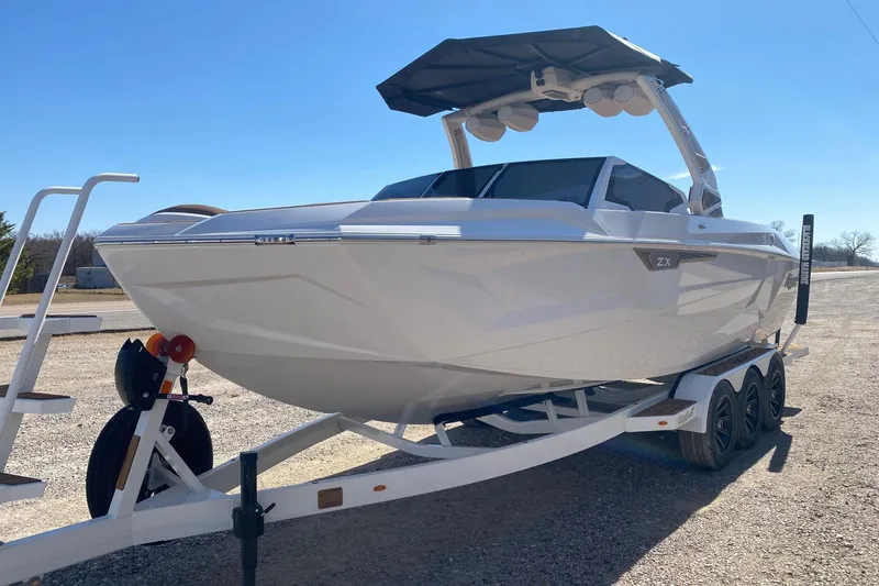 Slide: The Image of 2025 Tigé Ultré 25ZX boat on trailer, sleek design, sunny day. - 2