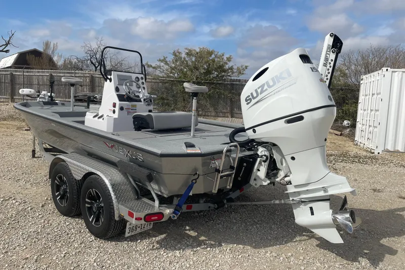 Slide: The Image of 2025 Vexus ACX2000 boat with Suzuki outboard motor on a trailer, parked outdoors. - 2