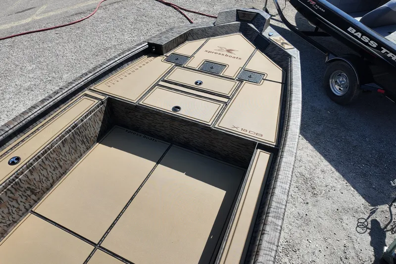 Slide: The Image of 2026 Xpress X18DB boat interior with tan deck and storage compartments. - 5