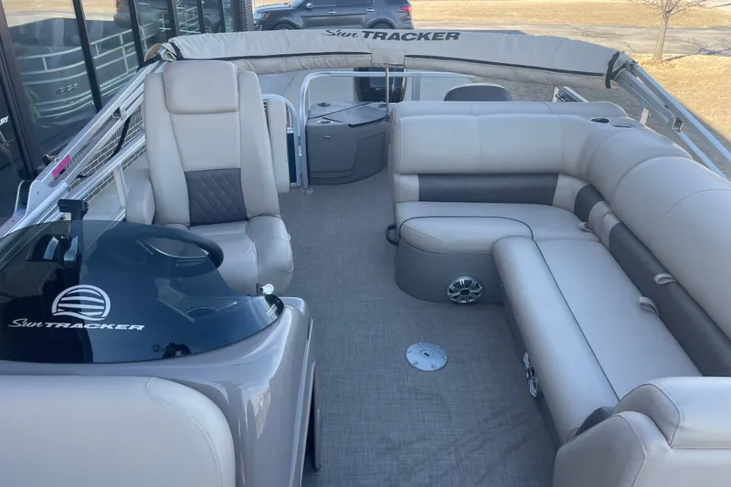 Slide: The Image of 2023 Sun Tracker Fishin' Barge 20 DLX interior with plush seating and helm. - 7