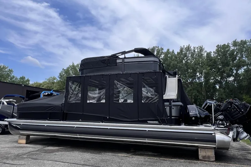 Slide: The Image of 2026 Premier Escalante pontoon boat with black canopy, parked outdoors. - 2