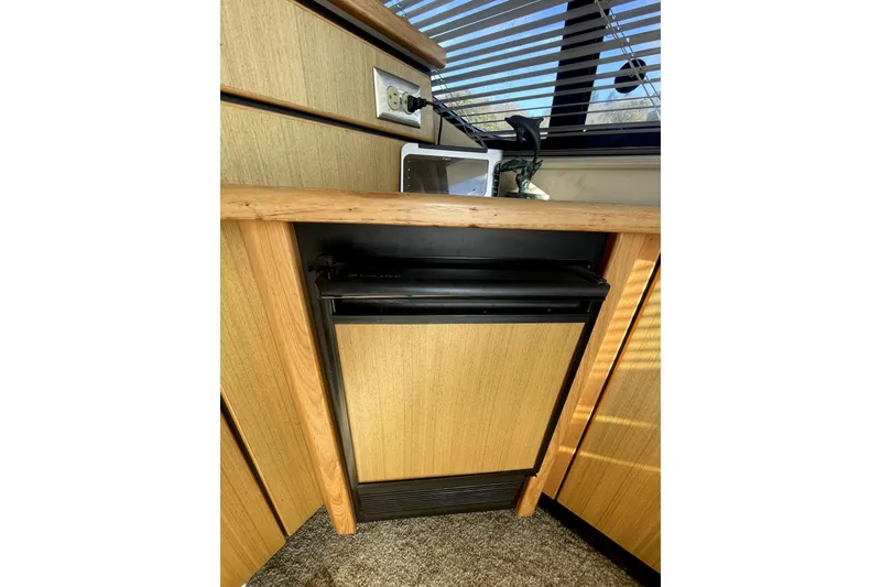 Slide: The Image of 2001 Bayliner 3988 Command Bridge Motoryacht interior with built-in mini fridge and wood paneling. - 10