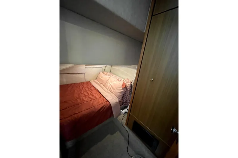 Slide: The Image of Cozy bedroom in 2001 Bayliner 3988 Command Bridge Motoryacht with red bedding and wooden cabinet. - 23
