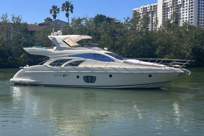 Slide: The Image of 2007 Azimut 55E yacht on calm water with lush greenery and buildings in the background. - 10