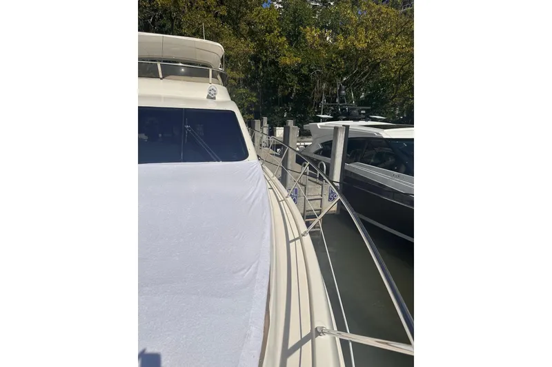 Slide: The Image of 2007 Azimut 55E yacht docked, side view with covered deck and railing. - 44