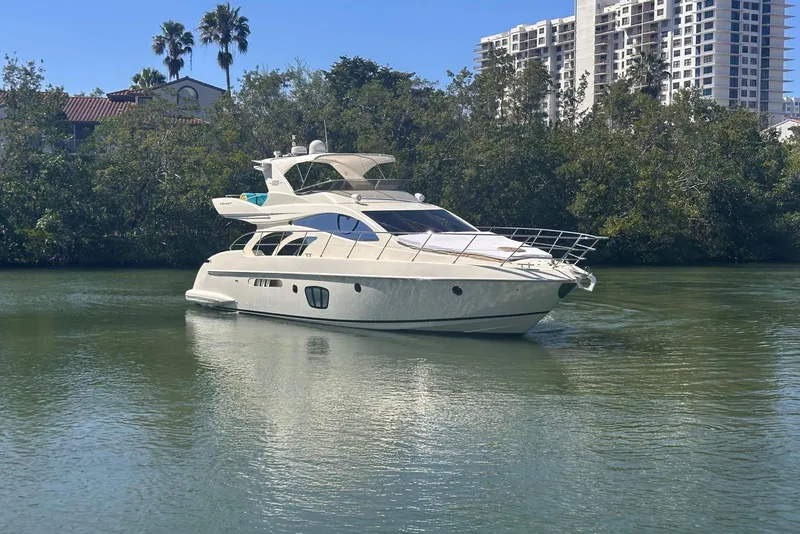 Slide: The Image of 2007 Azimut 55E yacht cruising on a calm river with lush greenery and buildings in the background. - 7