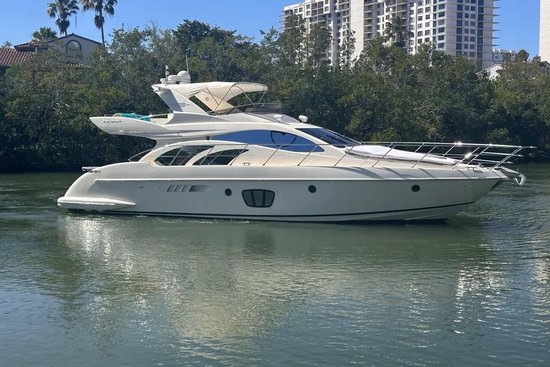 Slide: The Image of 2007 Azimut 55E yacht cruising on a calm river with lush greenery and buildings in the background. - 9