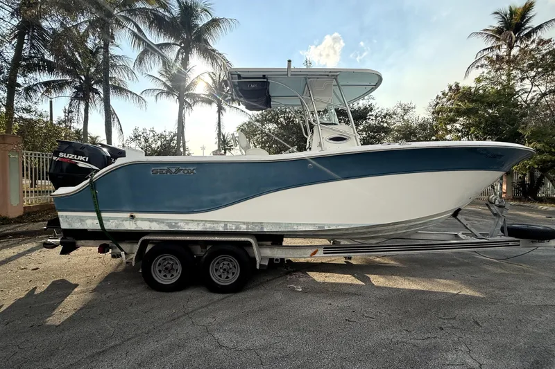 The Image of 2008 Sea Fox 256 Center Console boat on trailer, parked under palm trees. - 0