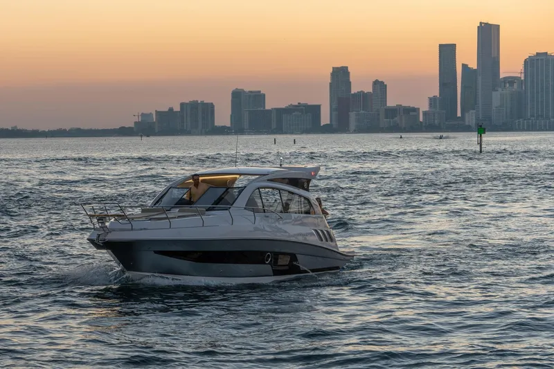 Slide: The Image of 2026 Hanover 375 yacht cruising at sunset with city skyline in background. - 116