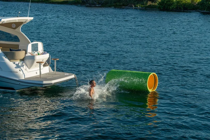 Slide: The Image of Person swimming near Hanover 375 boat, 2026 model, with floating green tube in water. - 123