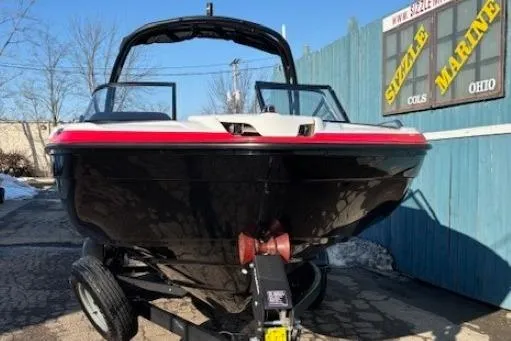 Slide: The Image of 2021 Yamaha Boats AR210 on trailer, black and red, parked outdoors. - 1