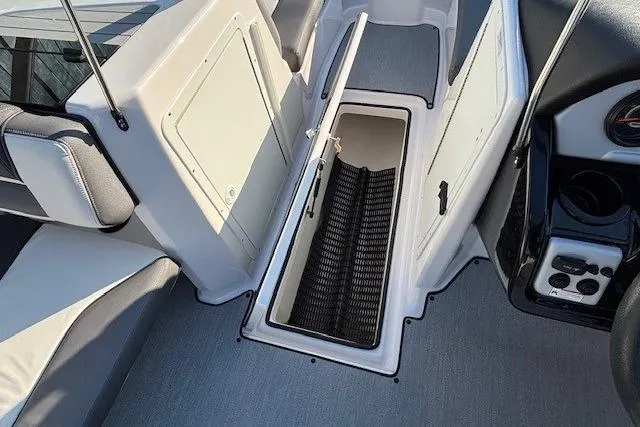 Slide: The Image of 2021 Yamaha AR210 boat interior storage compartment with open hatch and seating area. - 13