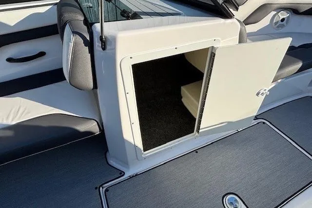 Slide: The Image of 2021 Yamaha AR210 boat interior storage compartment with open door, showcasing sleek design. - 14
