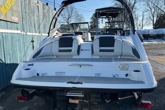 Slide: The Image of 2021 Yamaha Boats AR210, rear view, parked outdoors, showcasing sleek design and seating. - 3