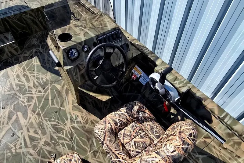 Slide: The Image of 2026 Lowe Roughneck RX2070 SC boat interior with camouflage design and steering console. - 2