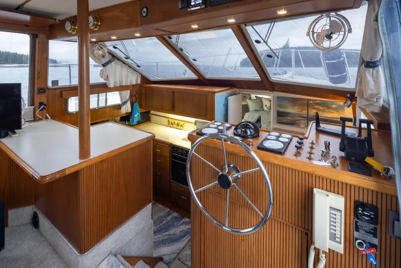 Slide: The Image of 1990 Tollycraft 44 Cockpit Motor Yacht interior with helm, wood paneling, and large windows. - 16