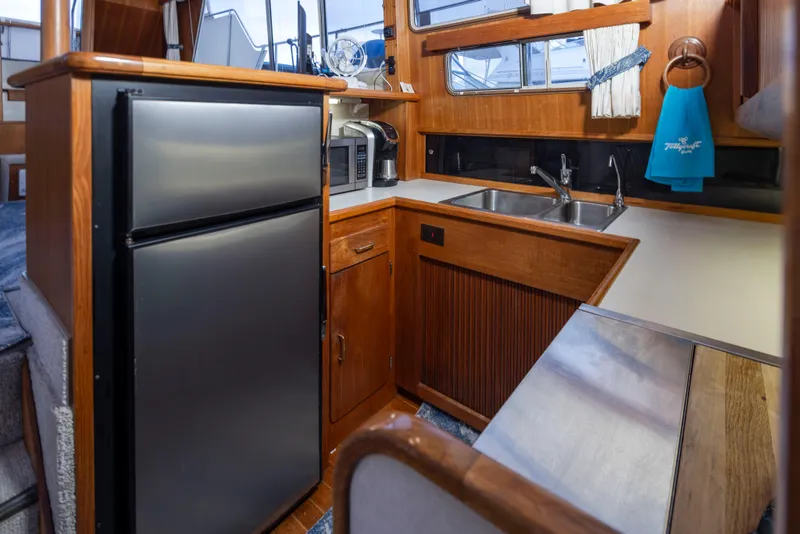 Slide: The Image of 1990 Tollycraft 44 Cockpit Motor Yacht kitchen with stainless steel appliances and wooden cabinetry. - 18