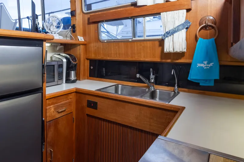 Slide: The Image of 1990 Tollycraft 44 Cockpit Motor Yacht kitchen with wood cabinetry, stainless steel appliances, and dual sink. - 19