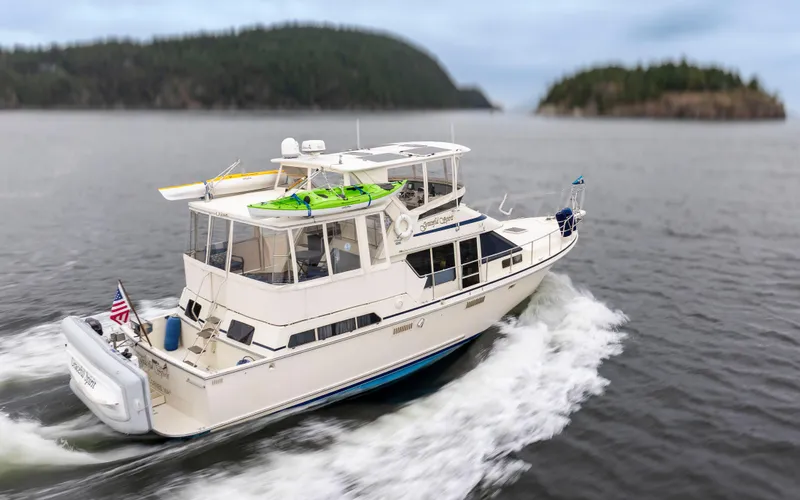 Slide: The Image of 1990 Tollycraft 44 Cockpit Motor Yacht cruising on open water with scenic island backdrop. - 3