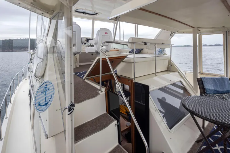 Slide: The Image of 1990 Tollycraft 44 Cockpit Motor Yacht interior with seating and table, overlooking serene waters. - 31