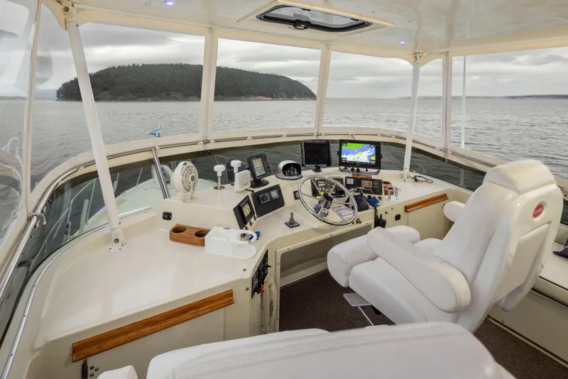 Slide: The Image of 1990 Tollycraft 44 Cockpit Motor Yacht helm with navigation equipment, overlooking serene waters. - 34