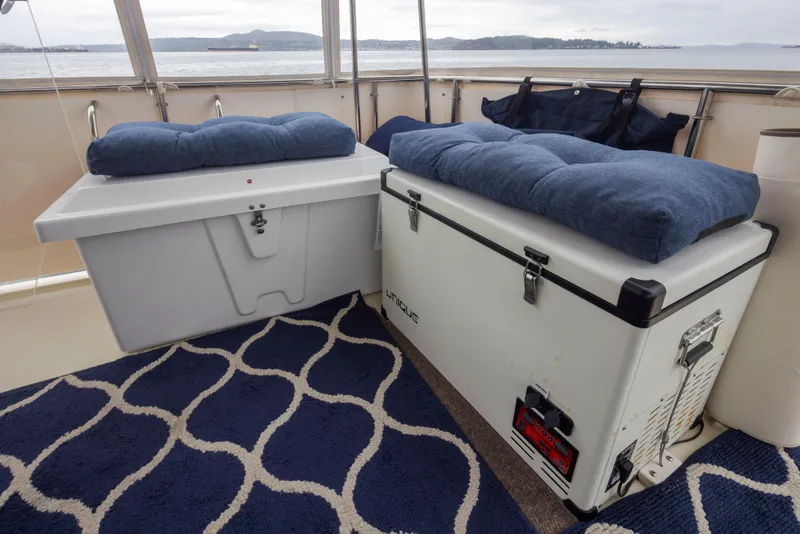 Slide: The Image of 1990 Tollycraft 44 Cockpit Motor Yacht interior with cushioned storage boxes and nautical decor. - 39