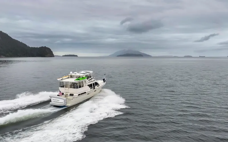 Slide: The Image of 1990 Tollycraft 44 Cockpit Motor Yacht cruising on open water under cloudy skies. - 42