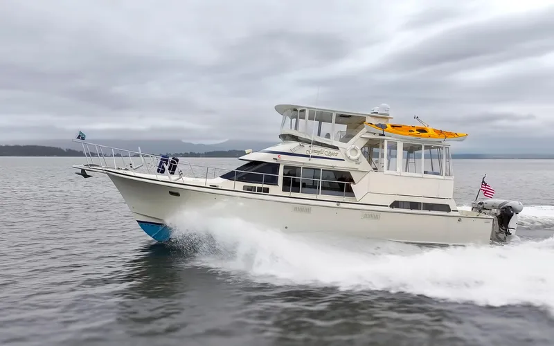 Slide: The Image of 1990 Tollycraft 44 Cockpit Motor Yacht cruising on open water under cloudy skies. - 8