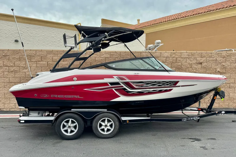 The Image of 2017 Regal 2000 ESX Bowrider boat on trailer, red and white design, parked outdoors. - 0