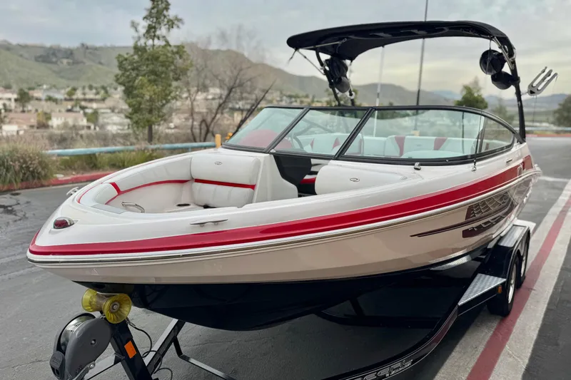 Slide: The Image of 2017 Regal 2000 ESX Bowrider boat with red accents on a trailer, parked outdoors. - 3