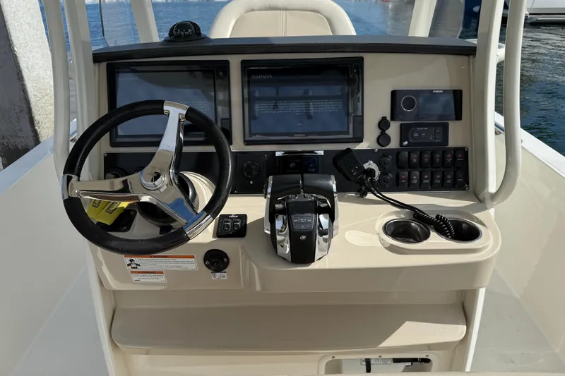 Slide: The Image of 2018 Boston Whaler 270 Dauntless helm with steering wheel, controls, and navigation screens. - 16