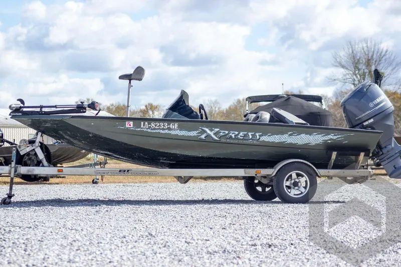 Slide: The Image of 2015 Xpress H17 boat on trailer with Yamaha outboard motor, parked on gravel. - 2