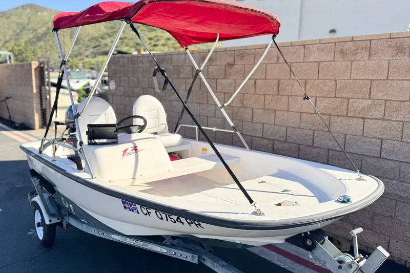 Slide: The Image of 2000 Boston Whaler 13 Sport boat with red canopy on trailer, parked outdoors. - 1