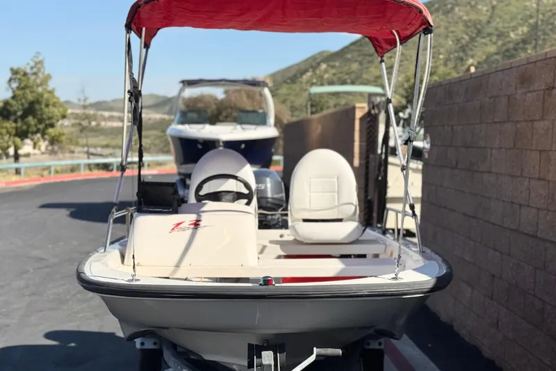 Slide: The Image of 2000 Boston Whaler 13 Sport boat with red canopy, parked outdoors. - 2