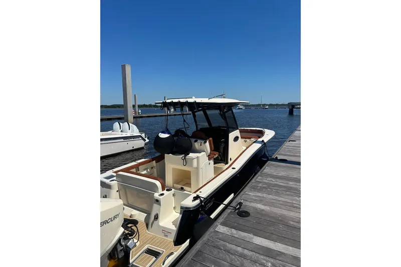 Slide: The Image of 2025 Scout 277 LXF boat docked at marina under clear blue sky. - 1