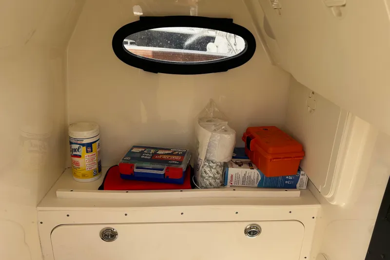 Slide: The Image of Interior storage of 2025 Scout 277 LXF boat with supplies and porthole window. - 31